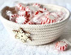 a bowl filled with candy canes sitting on top of a white cloth covered table