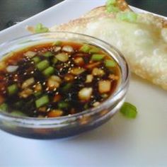 a white plate topped with food next to a small bowl of dipping sauce on top of it