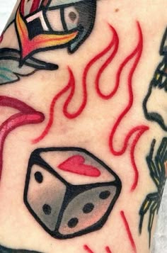 a close up of a person's arm with tattoos on it, including dices and flames