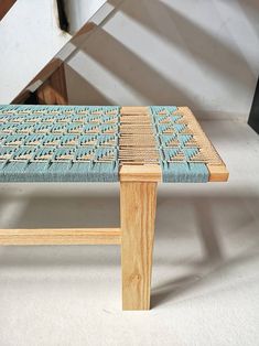 a bench made out of wood and woven with blue fabric on it's seat