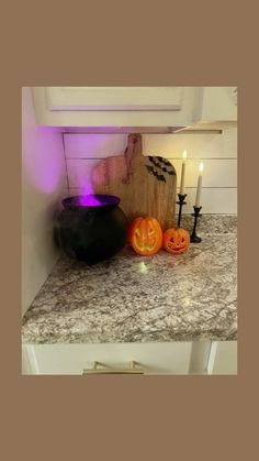 halloween decorations on a kitchen counter with purple light coming from the top and two pumpkins in front