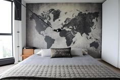 a bedroom with a large map on the wall above the bed and pillows in front of it