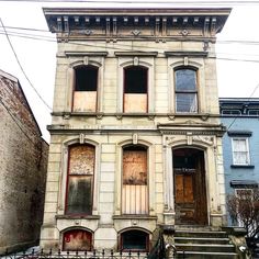 an old, run down house with boarded up windows and steps leading to the front door