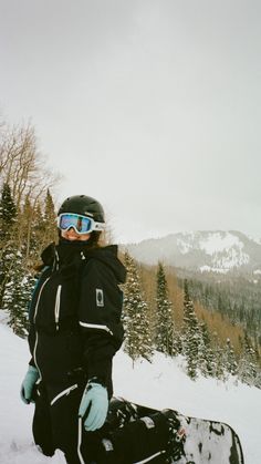 a person sitting in the snow with a snowboard on their feet and wearing goggles