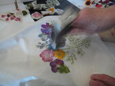 a person cutting fabric with scissors and flowers on it