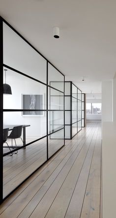 an empty room with wooden floors and glass partitions on the wall to divide it from the rest of the room