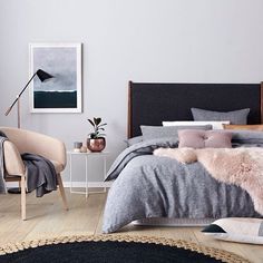 a bedroom with grey walls and white furniture, including a bed covered in fluffy blankets