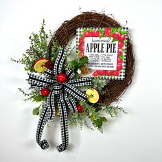 a wreath with apples and berries tied to it next to a sign that says apple pie