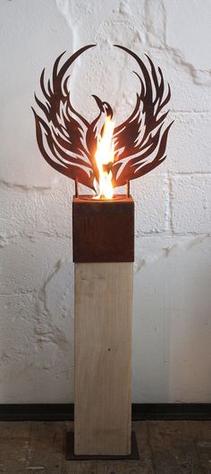 a sculpture made out of wood with flames in the shape of two birds on it