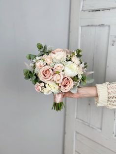 a person holding a bouquet of flowers in their hand with the door open behind them