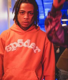 a man with dreadlocks wearing an orange hoodie