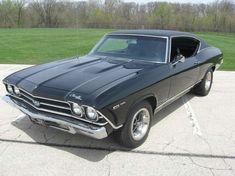 an old black muscle car parked in a parking lot