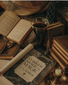 an old book and some candles on a table with other antique books, cups and glasses