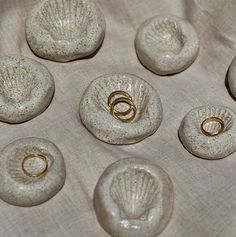 six seashells with wedding rings on them