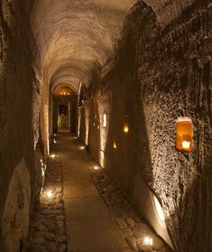 a long tunnel with lights on both sides and cobblestone walkway between two buildings