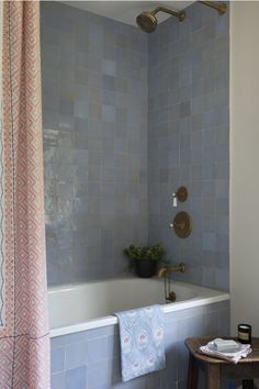 a bath tub sitting under a window next to a shower