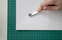 a person using a pair of tongs to cut paper on a piece of white paper