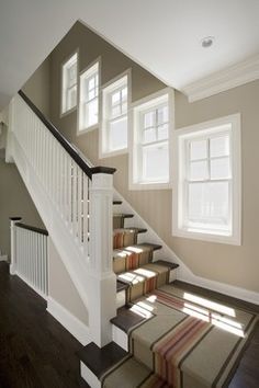 a staircase with carpeted steps leading up to two windows