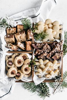 an assortment of cookies, pastries and desserts in wooden boxes on a white surface