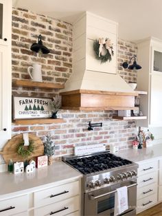 a kitchen with brick wall and white cabinets, stove top oven and wooden shelfs