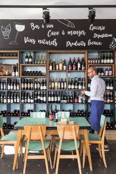 a man standing in front of a wine rack filled with bottles