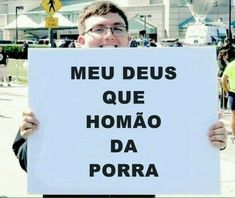 a man holding up a sign that says meu deus que homao da porra