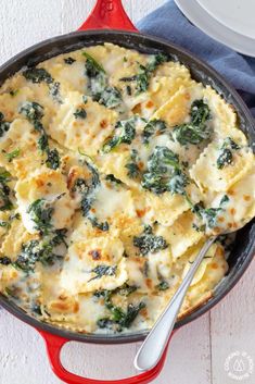 a skillet filled with spinach and cheese on top of a blue towel next to a white plate