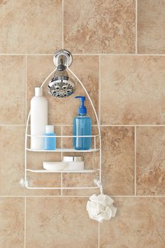 a bathroom shelf with soap, lotion and hand sanitizer on it next to a tiled wall