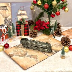 a table topped with christmas decorations and a train on top of a wooden board next to a tree