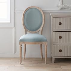 a chair sitting next to a dresser in a room