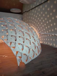 a large white sculpture sitting on top of a hard wood floor next to a wall