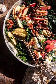 an apple and kale salad is shown in a bowl with spoons on the side