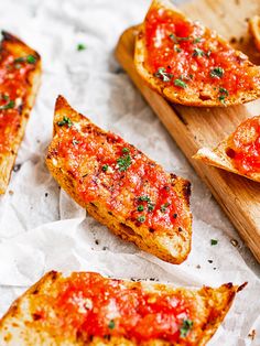 slices of bread with marinara sauce and parmesan cheese on them sitting on wax paper