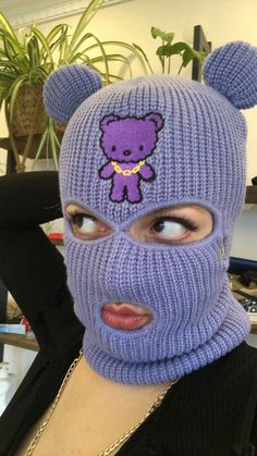 a woman wearing a purple knitted bear mask