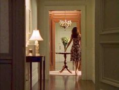 a woman in a dress walking into a house