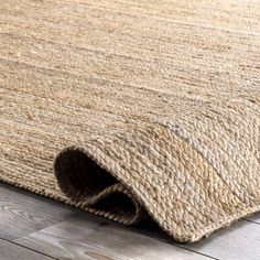 an area rug on the floor that is made out of jute and wood planks