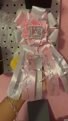 a person is holding onto some pink ribbons with the letter e on it and an embellishment in the middle