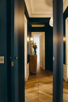 an empty hallway with wood flooring and black painted walls is seen from the doorway