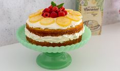 a cake with fruit on top sitting on a green plate next to a bottle of wine