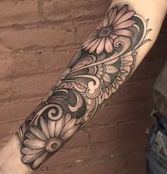 a woman's arm with flowers and swirls tattooed on the side of her leg