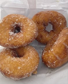 four sugared donuts in a white paper bag