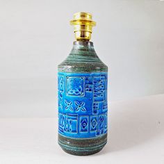 a blue and green glass bottle sitting on top of a white table next to a wall