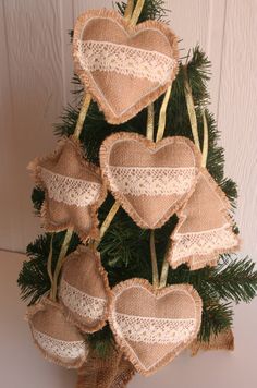 a small christmas tree with burlap hearts hanging from it's sides and pine needles