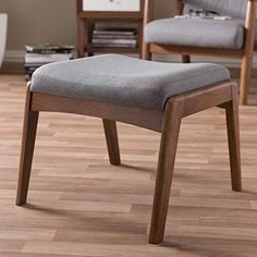 a gray chair sitting on top of a hard wood floor next to a book shelf