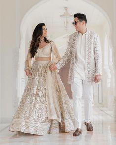 a man and woman in white outfits holding hands