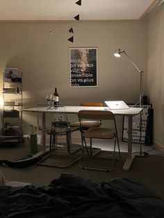 a room with a table, chair and lamp on the wall next to a bed