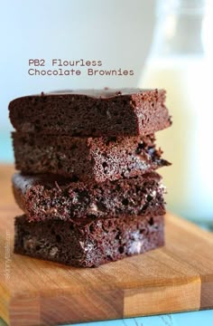 three pieces of chocolate brownies stacked on top of each other with milk in the background