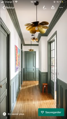 an empty hallway with wooden floors and green painted walls, along with large ceiling fan