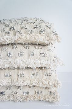 three white pillows stacked on top of each other with silver sequins and beads