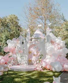 a white castle with pink and white balloons on the lawn at a princess themed birthday party